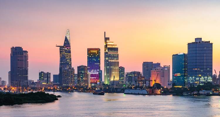 City skyline at sunset with notable buildings and river reflections.