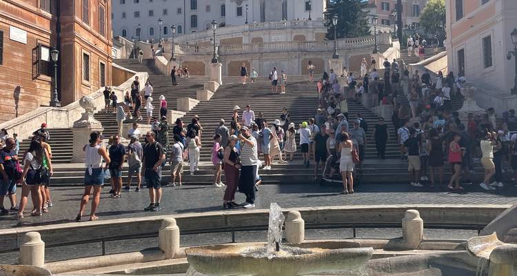 Belebtes Touristengebiet mit Stufen und einem Brunnen.
