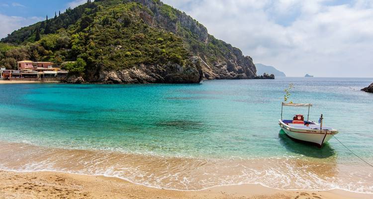Boot an einem türkisfarbenen Strand, umgeben von üppigem Grün.