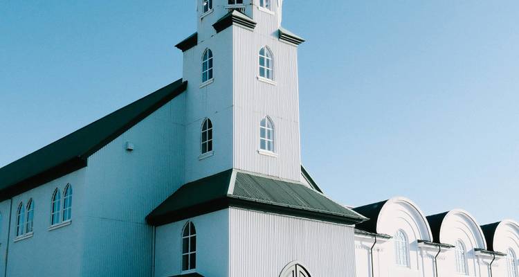 Una iglesia with una estructura metálica con torres contra un cielo azul despejado.