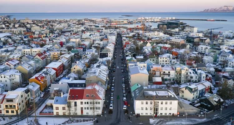Una vista aérea de Reikiavik con tejados cubiertos de nieve y un puerto.