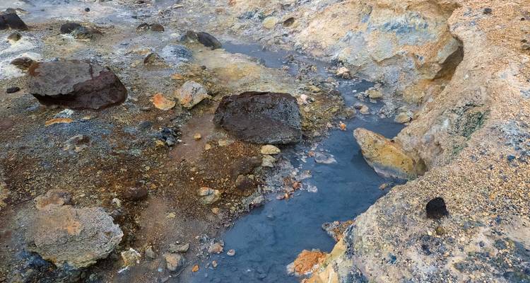 Geyser terrain with colorful rocks and water flowing.