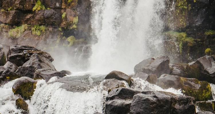 Rushing waterfall with large rocks at the base.