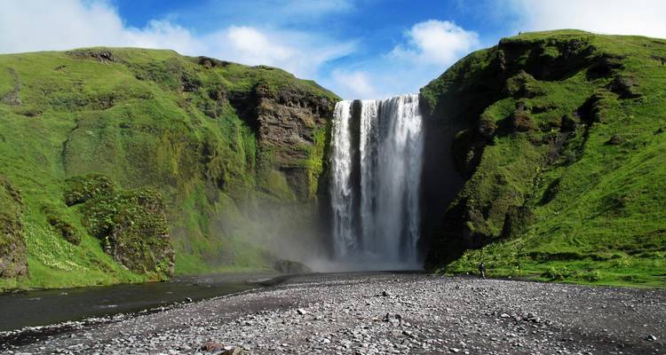 Large waterfall in a green valley with clear blue sky.