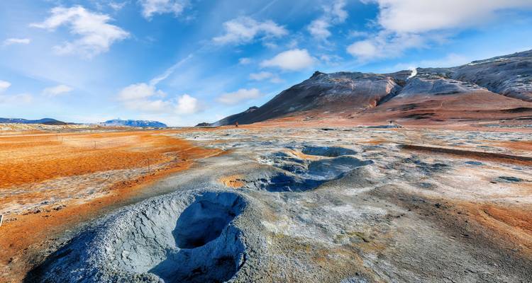 Geothermisches Gebiet mit buntem Boden und Dampfquellen.