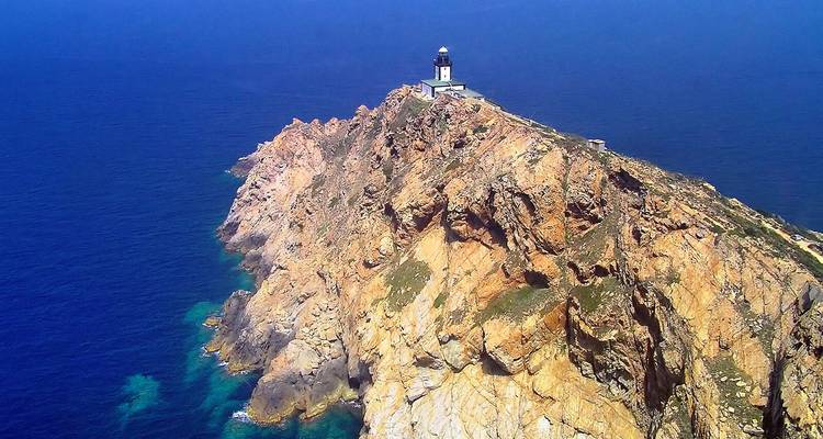 Costa rocosa de acantilados con faro en la punta bajo cielos despejados