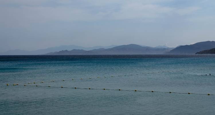 Mar en calma con línea de boyas y montañas distantes