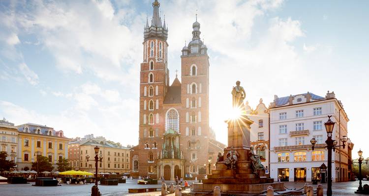 Sunlit square with intricate architecture and a prominent church.