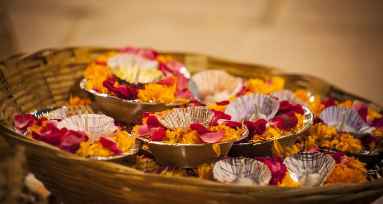 Basket filled with colorful flowers, petals, and small containers.