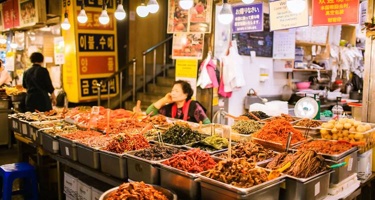 Un marché asiatique animé avec divers aliments frais exposés et un vendeur.