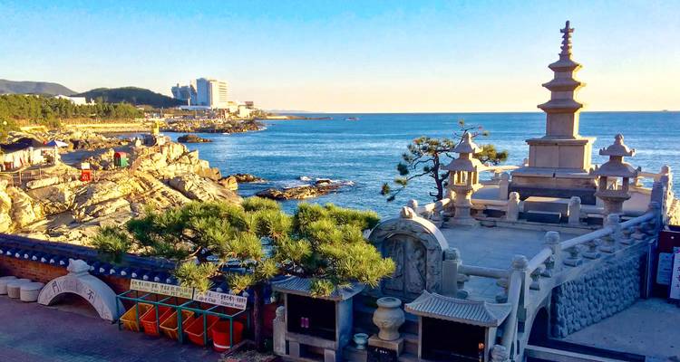 Vue côtière avec une pagode coréenne traditionnelle et la mer bleue en arrière-plan.