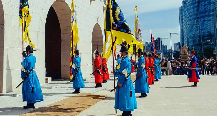 Gardes militaires coréens traditionnels en uniformes colorés exécutant un rituel.