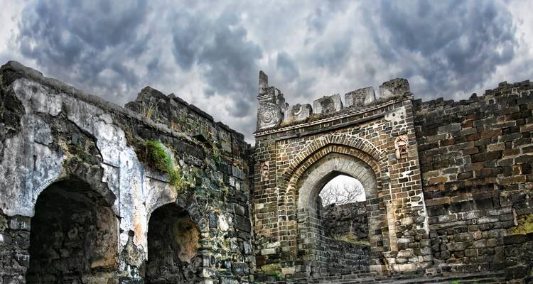 Antiguas ruinas de piedra bajo un cielo dramático y nublado.