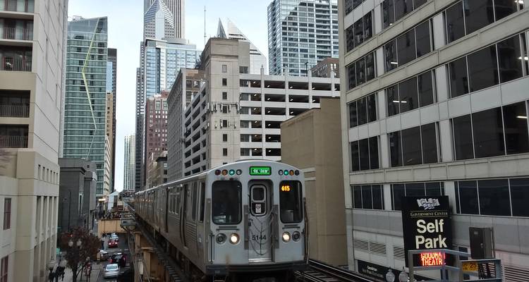 Train sur des voies surélevées avec des gratte-ciel modernes en arrière-plan.