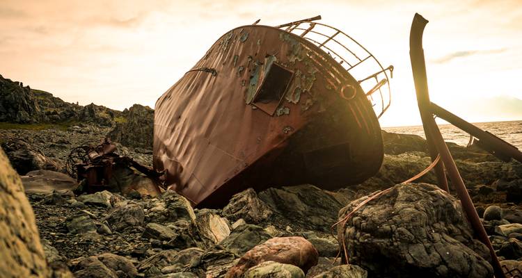 Épave de navire rouillée et abandonnée sur un rivage rocheux.