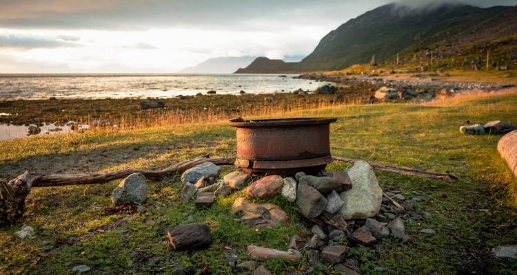 Paysage avec foyer au bord de l'eau au coucher du soleil.
