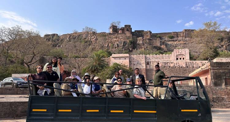 Group of tourists in a safari jeep in front of a fort.