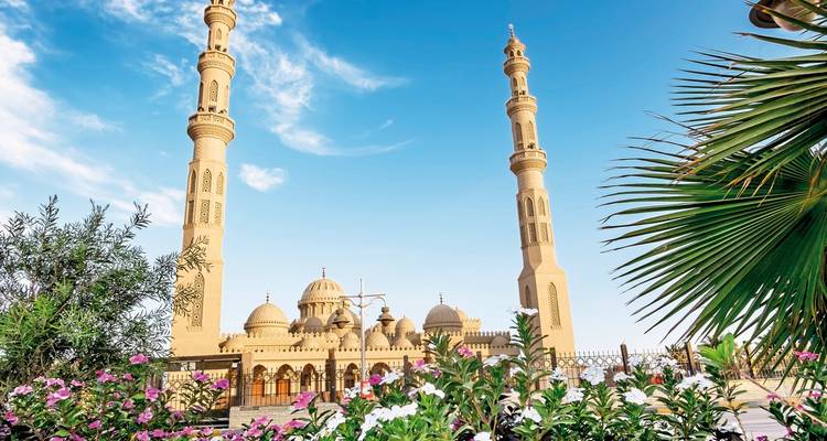 Eine prächtige Moschee mit hohen Minaretten und bunten Blumen im Vordergrund.