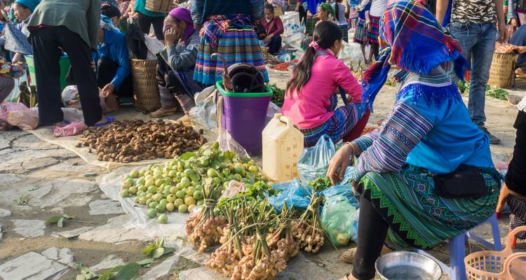 Bustling hill-tribe market with women in colourful headscarves selling fresh produce and ginger.