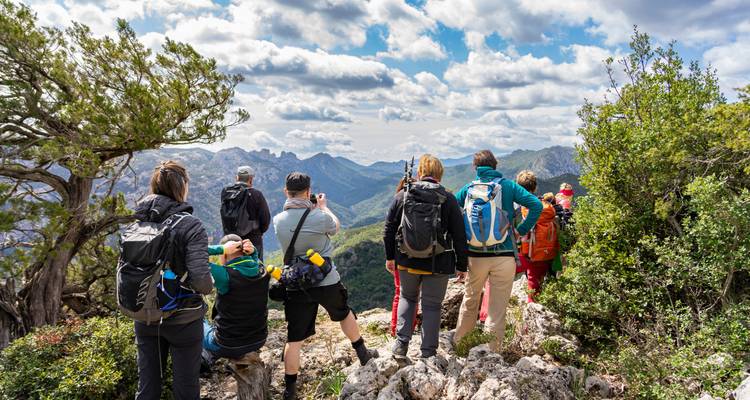 Groep trekkers geniet van het panoramische bergzicht vanaf een rotsachtige bergrug op Sardinië.