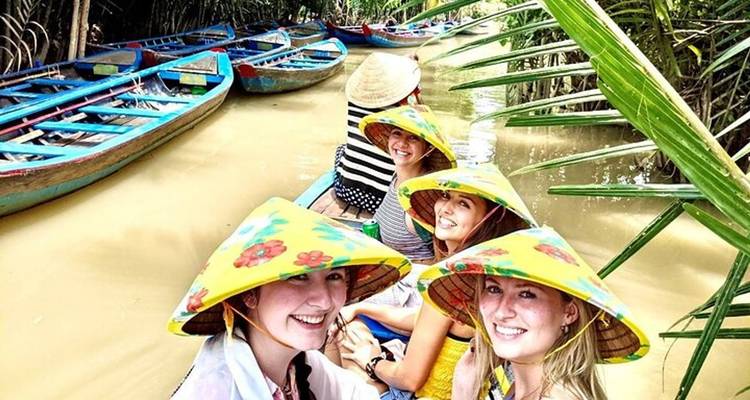 Group of people in a boat with colorful hats on a river.