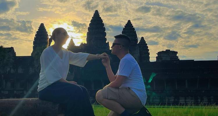 Couple at sunset in front of Angkor Wat silhouette.