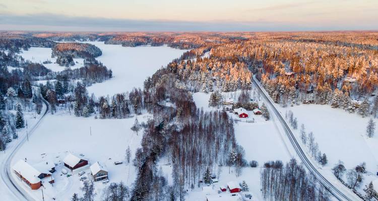 Luftaufnahme von schneebedecktem Wald und Seen.