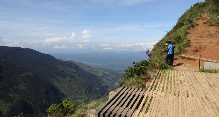 Person, die eine malerische Berglandschaft von einem Aussichtspunkt aus betrachtet.