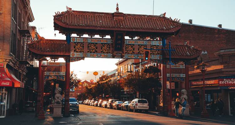 Arche décorative d'un quartier culturel avec des voitures garées.