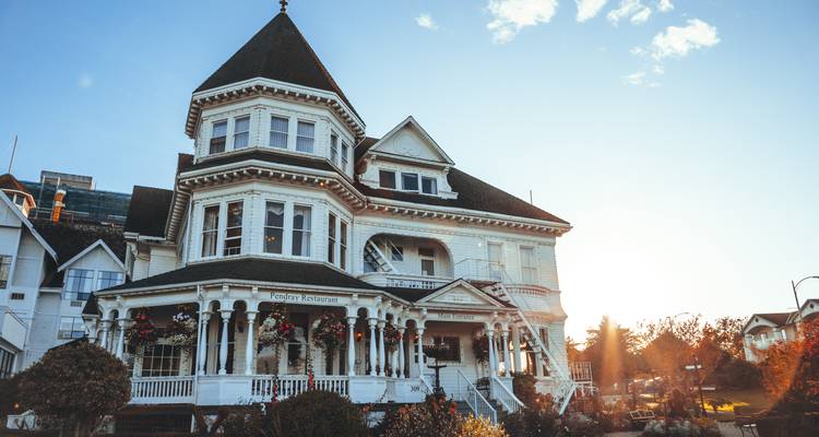 Maison à l'allure historique avec un porche pittoresque sous un soleil en contre-jour.