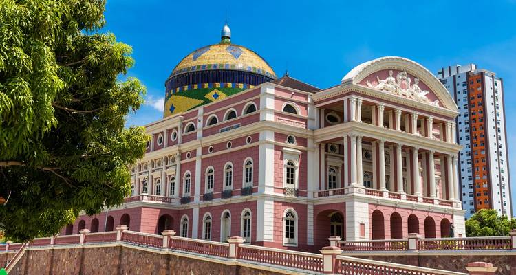Teatro de la Ópera Amazonas de color rosa brillante con cúpula de azulejos bajo un cielo azul despejado en Manaos
