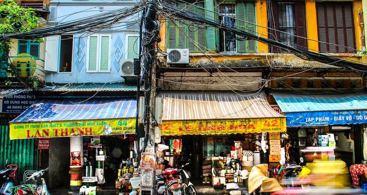Kleurrijke winkelpuien en warrige elektrische kabels sieren een levendige straat in Hanoi.