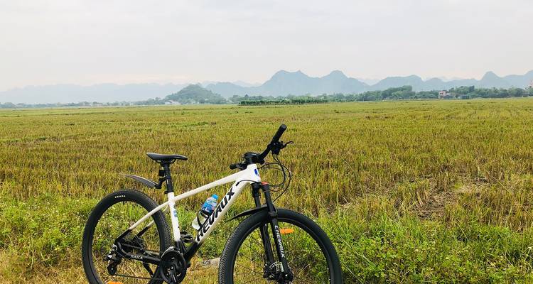 A bicycle in a vast field with distant hills in the background.
