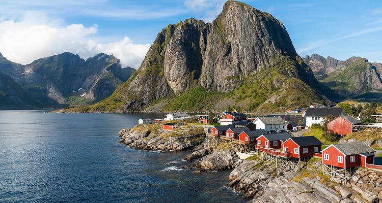 Des cabanes de pêcheurs rouges sont situées sur les rivages rocheux sous les pics imposants des îles Lofoten.
