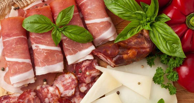 Variété de viandes et fromages aux herbes sur un plateau.