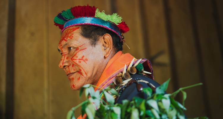 Hombre indígena tradicional con pintura facial y tocado.