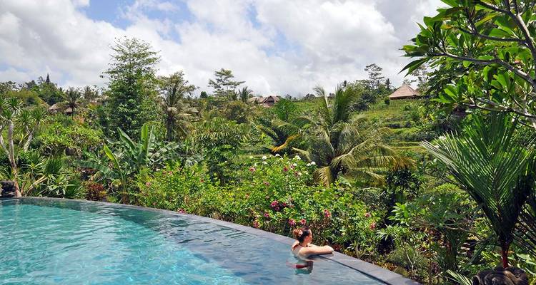 Frau in einem Infinity-Pool mit Waldblick.