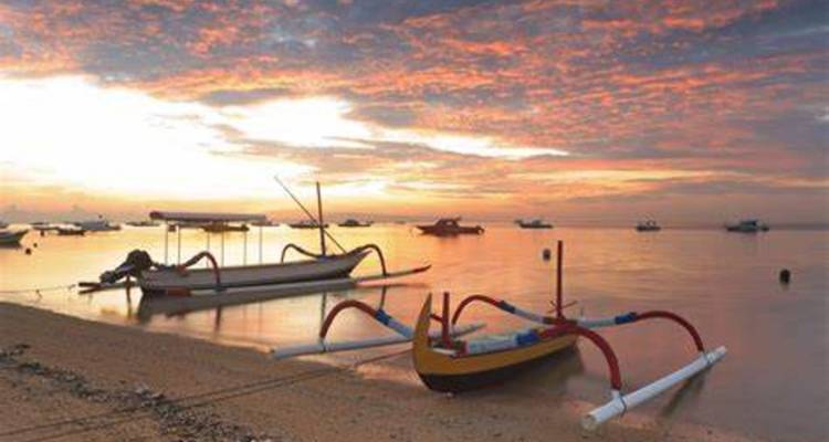 Traditionelle Boote an einem Strand mit einem farbenfrohen Sonnenuntergang.