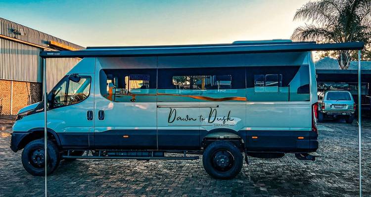 Modern safari minibus parked on cobblestone with custom livery reading "Dawn to Dusk Safaris".