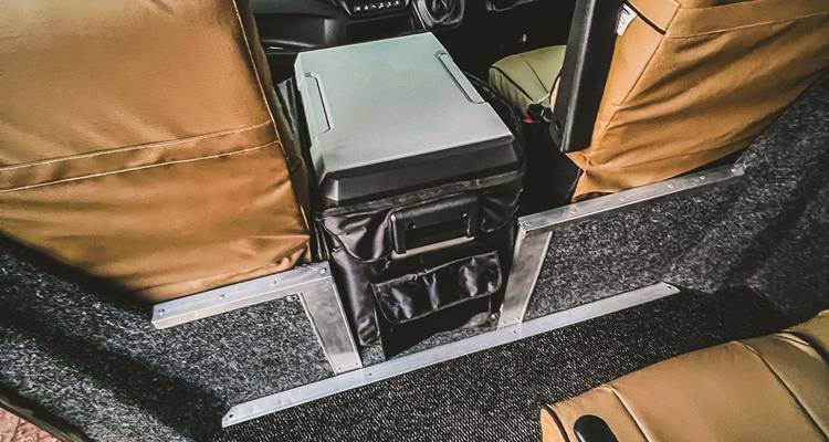 Close-up of central console and storage box between tan passenger seats inside the vehicle.