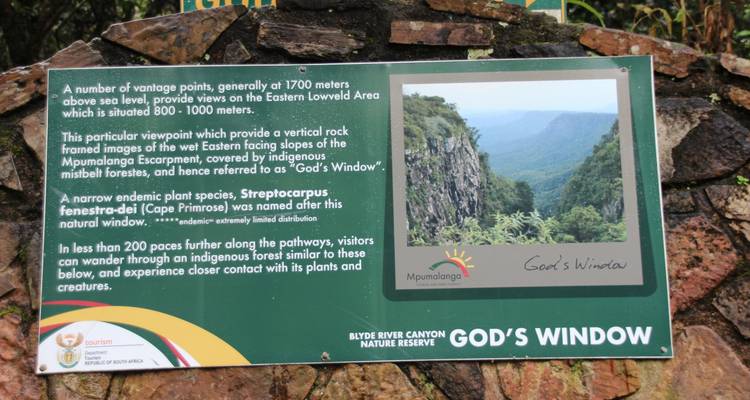 Informational signboard describing the viewpoint known as God's Window overlooking lush cliffs in Mpumalanga.