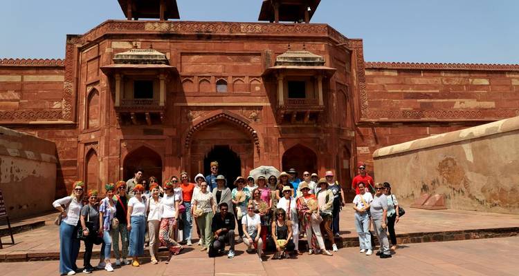 Eine große Gruppe von Touristen, die vor einem roten Sandsteingebäude posiert.
