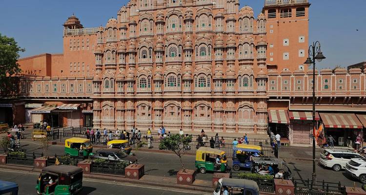 Hawa Mahal in Jaipur mit Rikschas und Menschen im Vordergrund.