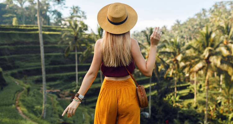 Frau mit Strohhut blickt über Terrassenfelder.