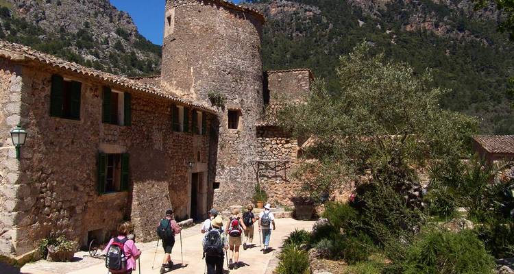 Group of people walking towards an old stone building in a rural area.