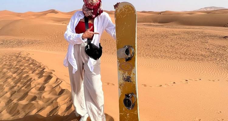 Persoon met een sandboard in de woestijn.