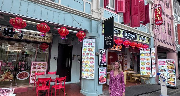 Femme en robe rose debout sur Smith Street dans le quartier chinois de Singapour, entourée de lanternes rouges et de menus de nourriture
