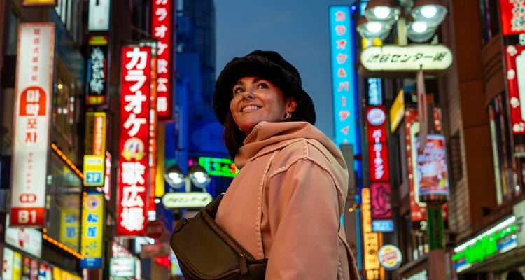 Person in a city with bright advertising signs at dusk.