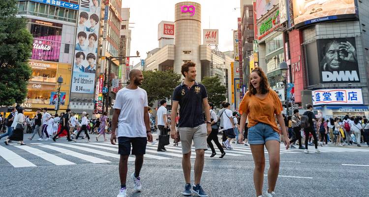 People crossing a famous street crosswalk with store signs in the background.