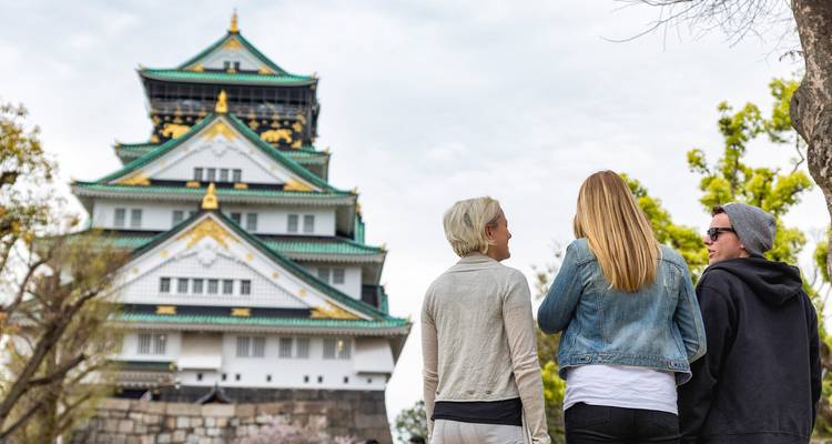 Three people observing a traditional castle.
